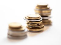 Side view of stacks of coins increasing in height, on white studio background